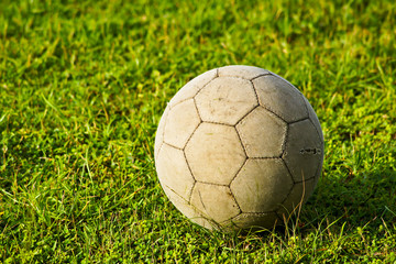 Old soccer ball on the green grass.