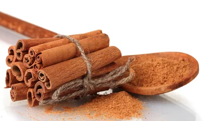 Foto auf Acrylglas Cinnamon sticks and powder in wooden spoon isolated on white © Africa Studio