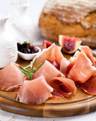 Dry cured ham with olives and fig on chopping board