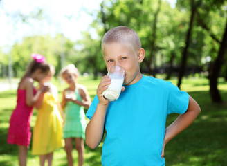 Fototapeta premium Boy drinking milk in the summer park