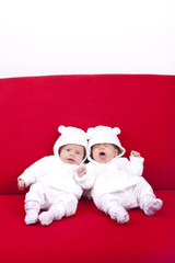 eineiige Zwillinge ( Schwestern ) auf einem roten Sofa