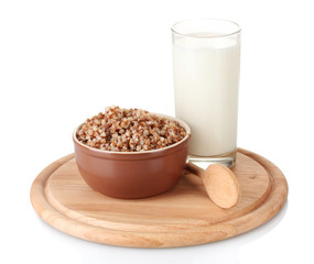 Boiled buckwheat in a brown bowl a glass of milk
