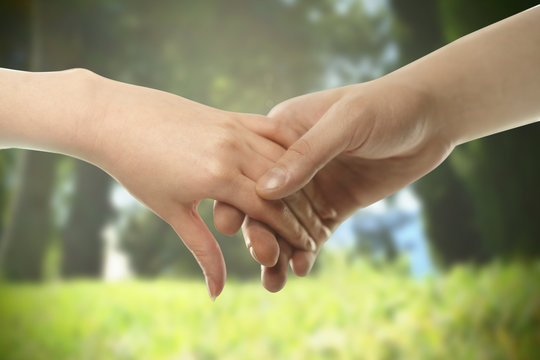 Couple hands closed together outdoors. Hand-in-hand