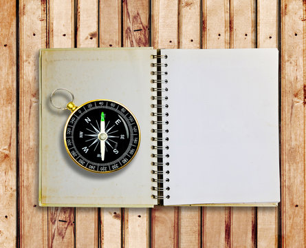 Compass and Old notebook on wood panels for background