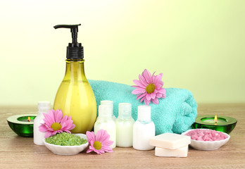 Hotel amenities kit on wooden table on green background