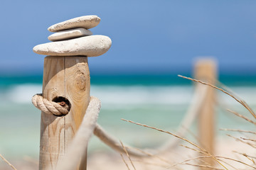 Stones balanced on wooden banister near the beach.