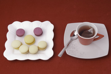 Fototapeta na wymiar Cup of tea and smile of macaroons on velvet tablecloth