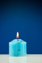 Close up of burning candle against dark blue background