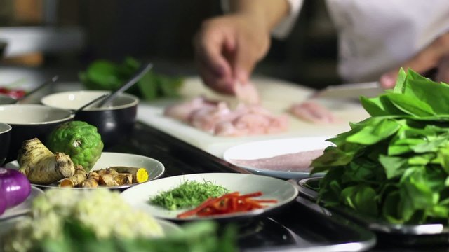 Professional asian cook chopping fish in restaurant kitchen