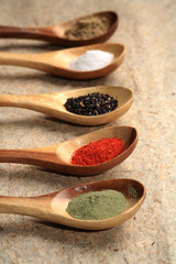 Colored spices on wooden spoons.