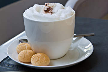 Hot cappuccino or latte coffee with frothed milk and cookies