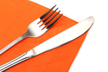 Fork and knife in a orange cloth isolated on white