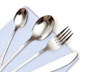 Fork, spoon and knife in a blue cloth  isolated on white