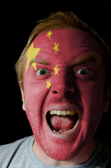 Face of crazy angry man painted in colors of Chna flag