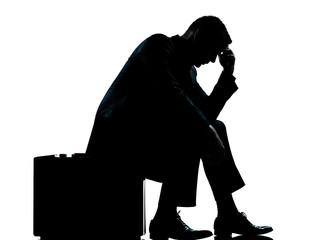 one business man sitting on suitcase tired despair silhouette