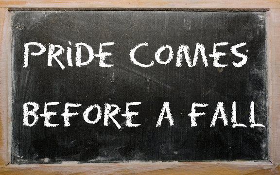 Proverb "Pride comes before a fall" written on a blackboard