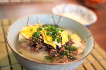 Bowl of Korean dumpling soup with shredded beef and egg.