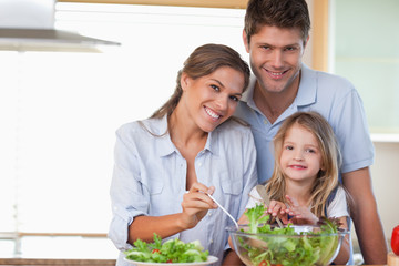 Smiling family preparing a salad