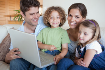 Fototapeta na wymiar Smiling family using a laptop