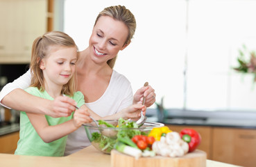 Obraz na płótnie Canvas Mother and daughter stirring salad