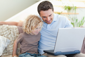 Fototapeta premium Father and son with laptop on the sofa