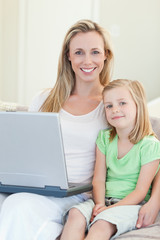 Mother and daughter with laptop on sofa