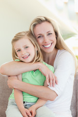 Mother hugging her daughter on couch