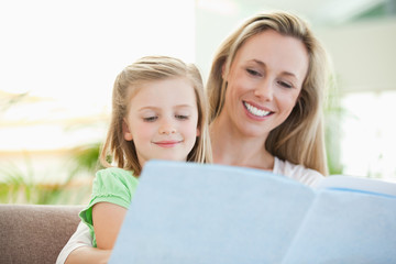 Mother and daughter reading a magazine on the couch