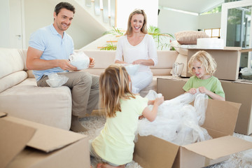 Family unpacking cardboard box in the living room