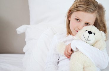 Girl with her teddy sitting on the bed