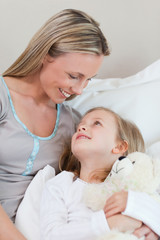 Obraz na płótnie Canvas Mother hugging her daughter on the bed