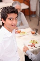 Obraz na płótnie Canvas Young waiter serving lunch