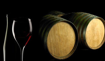 red wine glass and barrels on black background