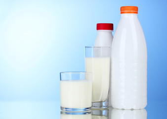 Tasty milk in glasses and bottle on blue background