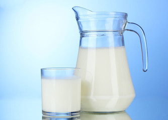 Tasty milk in jug and glass on blue background
