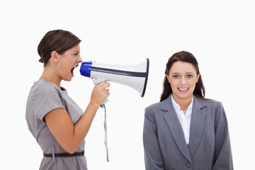 Businesswoman using megaphone to yell at colleague