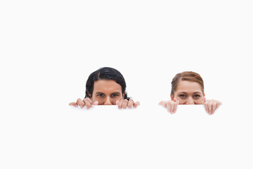 Sneaky couple looking over blank wall