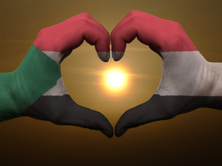 Heart and love gesture by hands colored in sudan flag during bea