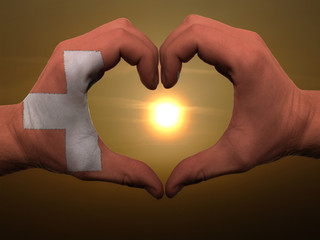 Heart and love gesture by hands colored in swiss flag during bea