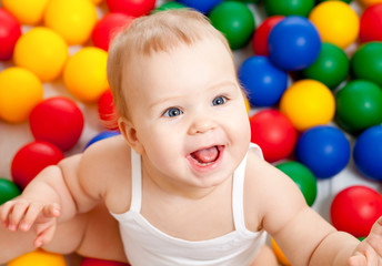 Portrait of a smiling infant sitting among colorful balls