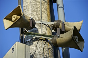 Three public loudspeakers hanged on concrete pillar
