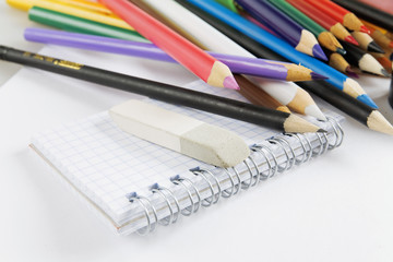Multi-colored pencils and notepad on a white background