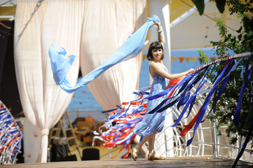 Young woman is holding a material on a bridge with ribbons