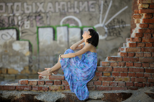 Attractive girl sitting on a brick destroyed wall