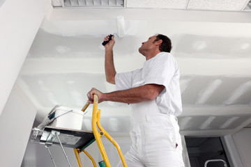 Tradesman painting a ceiling - Powered by Adobe
