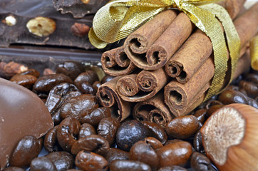 coffee cup and beans, cinnamon sticks, nuts and chocolate