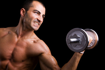 Fototapeta na wymiar Young man lifting weights against black background