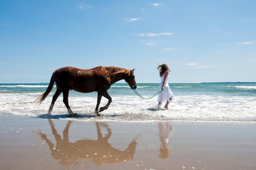 Girl exercising horse at the beach