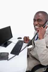 Side view of a businessman answering the phone while using a mon