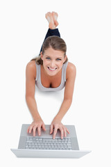 Portrait of a woman using a notebook while lying on the floor